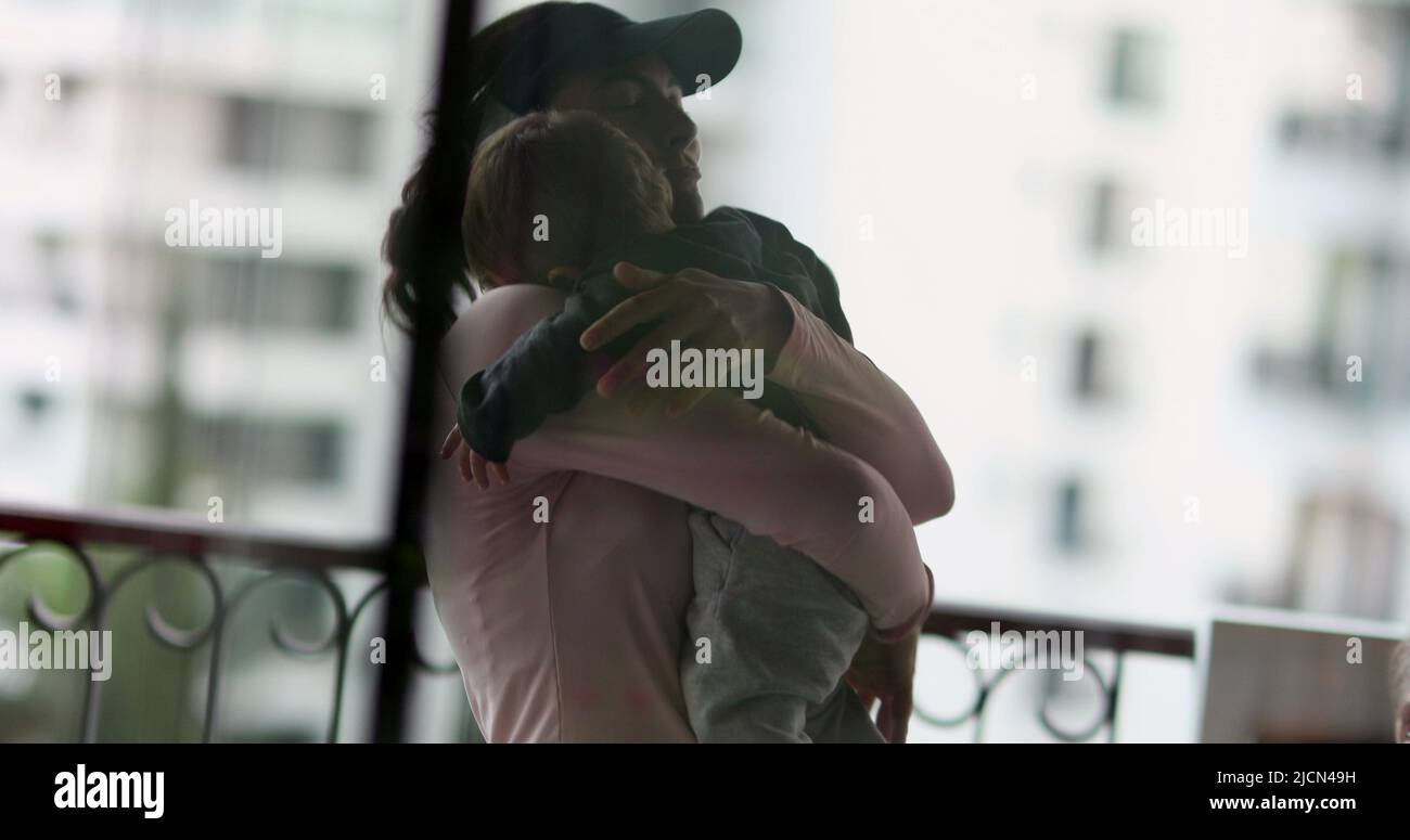 Silhouette of mother picking up baby in arms loving relationship. Mom