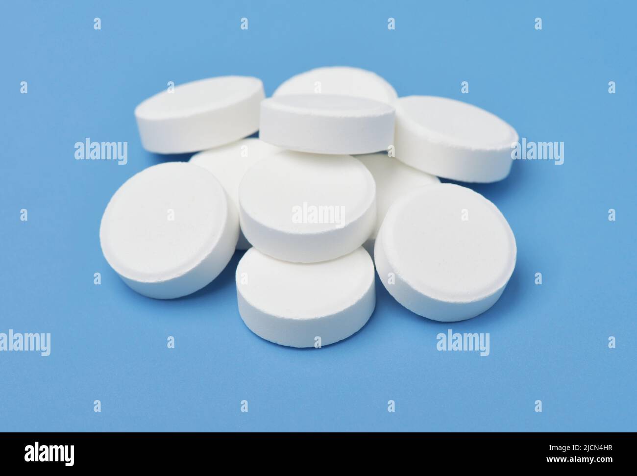 Group of white medical pills isolated on blue background Stock Photo
