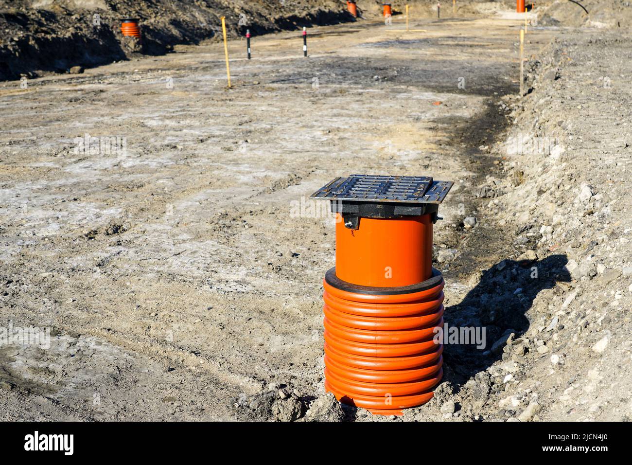 New storm water drainage well with black iron grate cover and brown plastic sewer pipe on a new street construction site Stock Photo