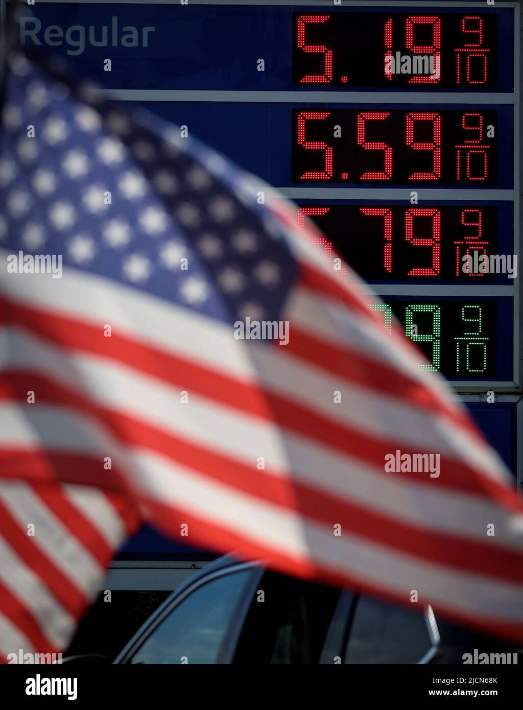Gasoline prices are displayed at an Exxon gas station behind American flag in Edgewater, New Jersey, U.S., June 14, 2022. REUTERS/Mike Segar Stock Photo