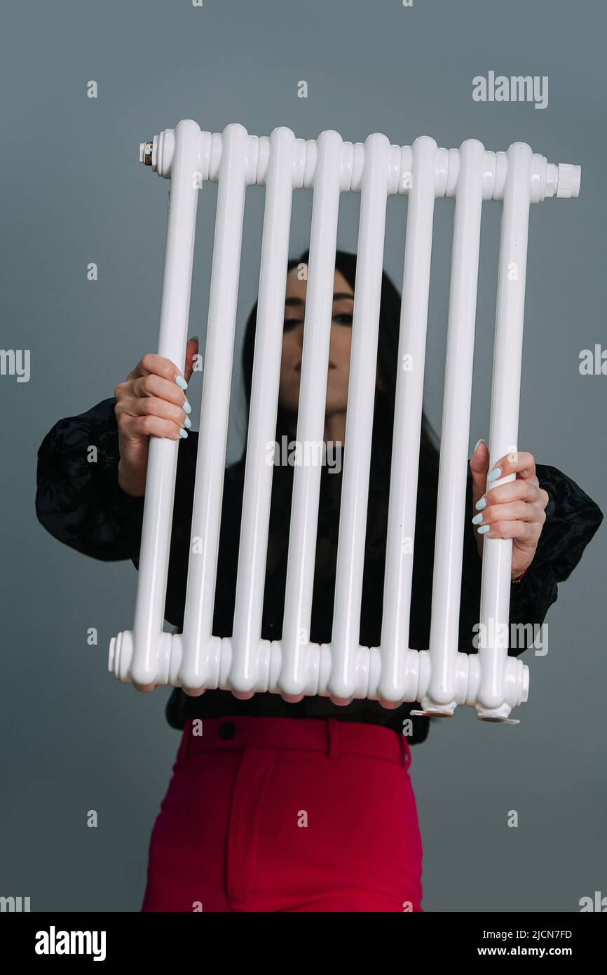 Woman holding a heating radiator in front of her face. Stock Photo