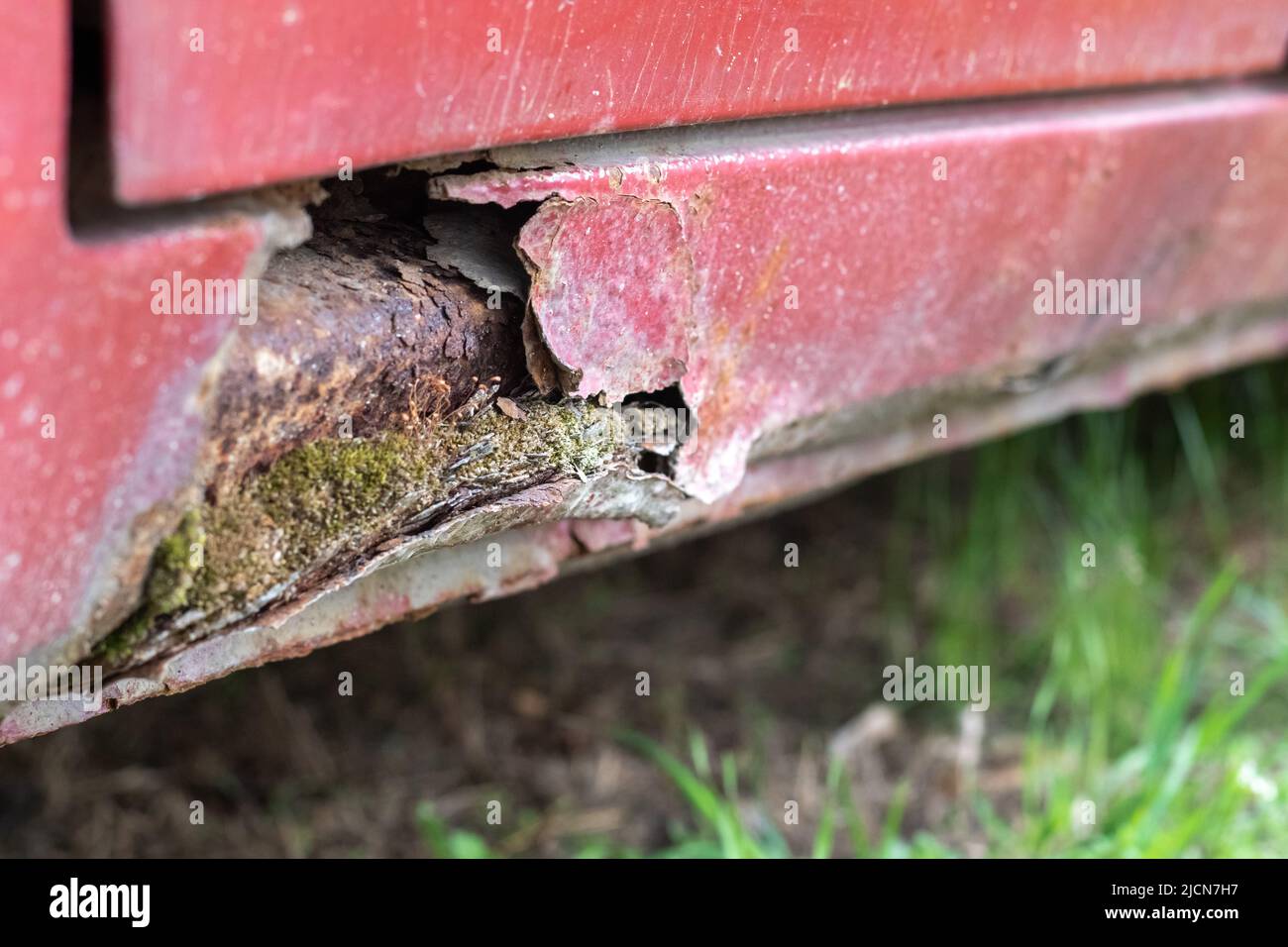 Rusty driver's door sills. Corrosion of the body of a red old car after
