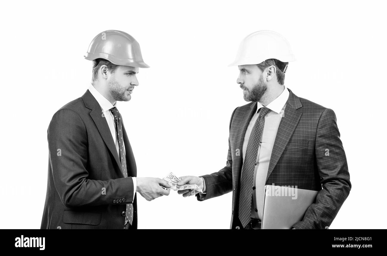 confident businesspeople men in suit and safety helmet giving money and hold computer, bribe Stock Photo