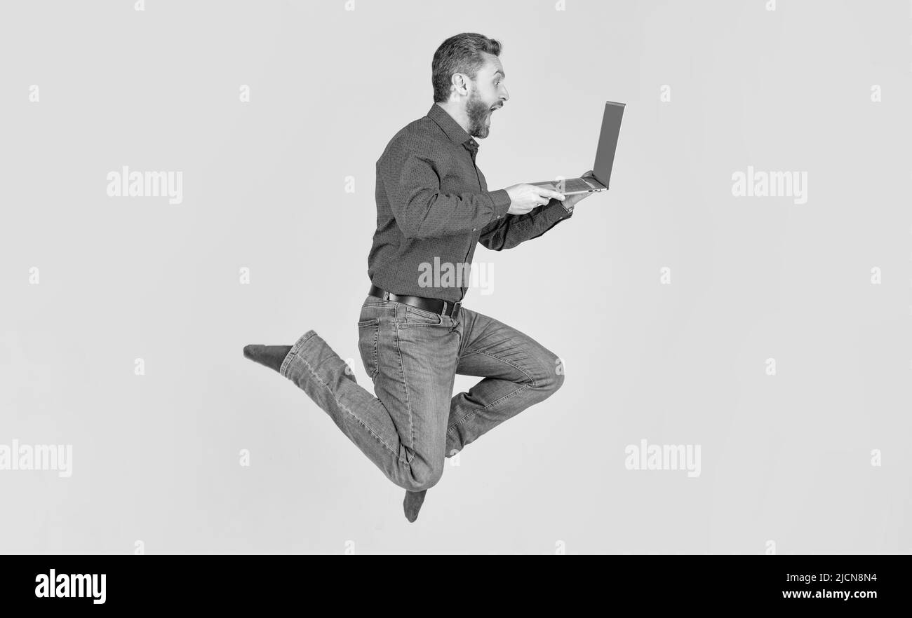 surprised energetic jumping man running working online on laptop hurry up for shopping, business Stock Photo