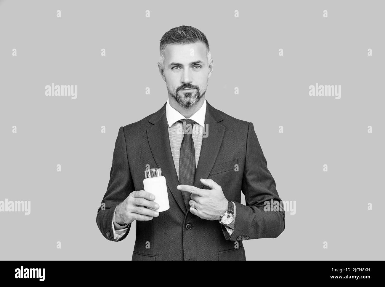 confident businessman man in businesslike suit presenting medical product of pill jar, drug business Stock Photo