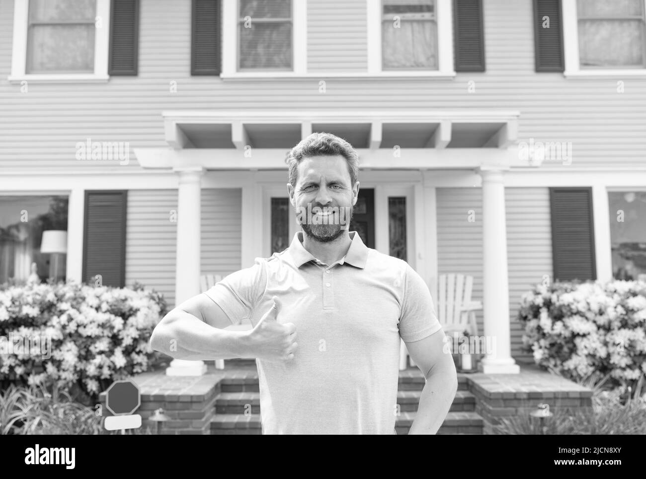 happy owner show thumb up. ownership. confident man outside new american home. Stock Photo