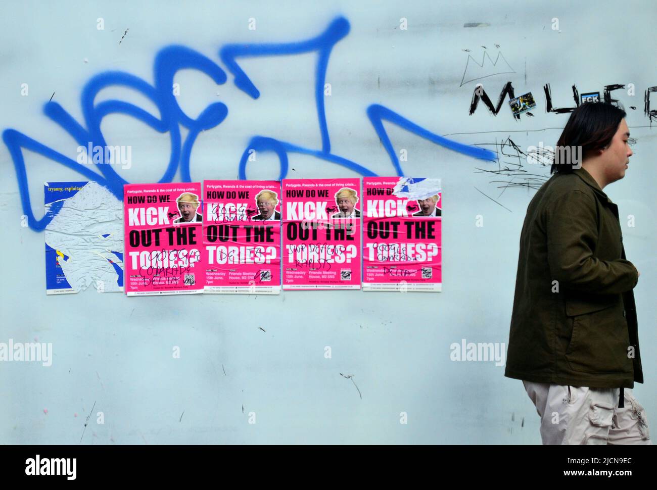 Man walks past 'Kick Out the Tories' posters on a window with graffiti on it in Manchester, England, United Kingdom, British Isles Stock Photo