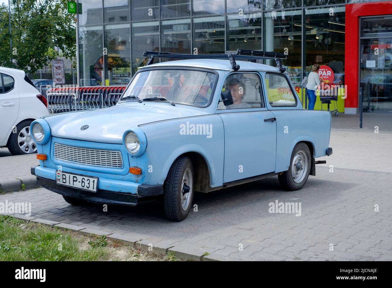 elderly woman sitting in the driving seat of her old trabant car at supermarket carpark lenti zala county hungary Stock Photo