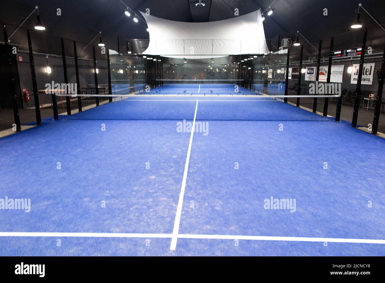View of an empty blue padel court. Padel is a mix between Tennis and Squash. It's usually played in doubles on an enclosed court. Stock Photo