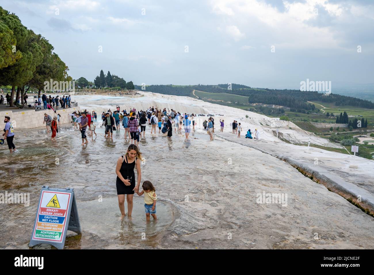 Tourists enjoy the thermal pools of travertines terraces. Pamukkale, Türkiye. Stock Photo