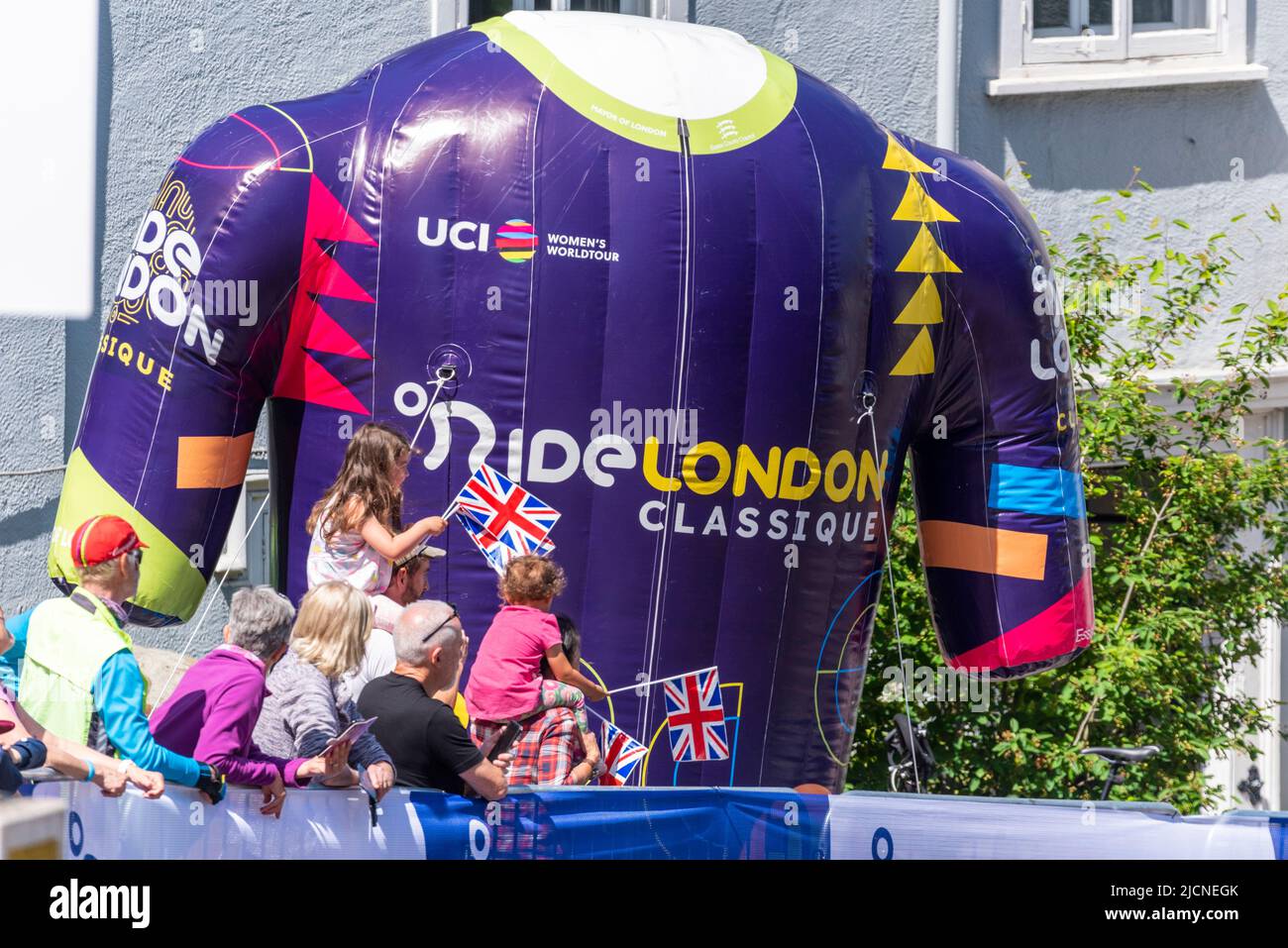 Advertising inflatable at the RideLondon Classique women's cycle race, with young supporters waving Union Jack flags. Children. Girls Stock Photo