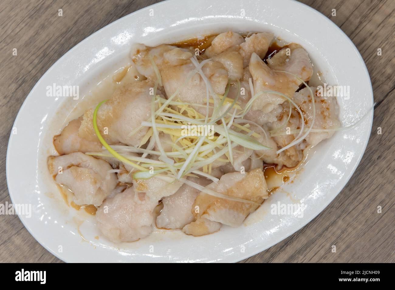 Overhead view of steamed fish fillets in ginger sauce and piled high on the plate for a great Chinese food meal. Stock Photo