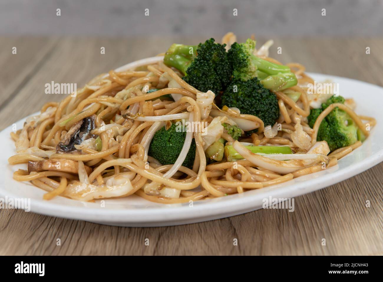 Generous plate of vegetable noodles glazed in sauce and piled high on the plate for a great Chinese food meal. Stock Photo