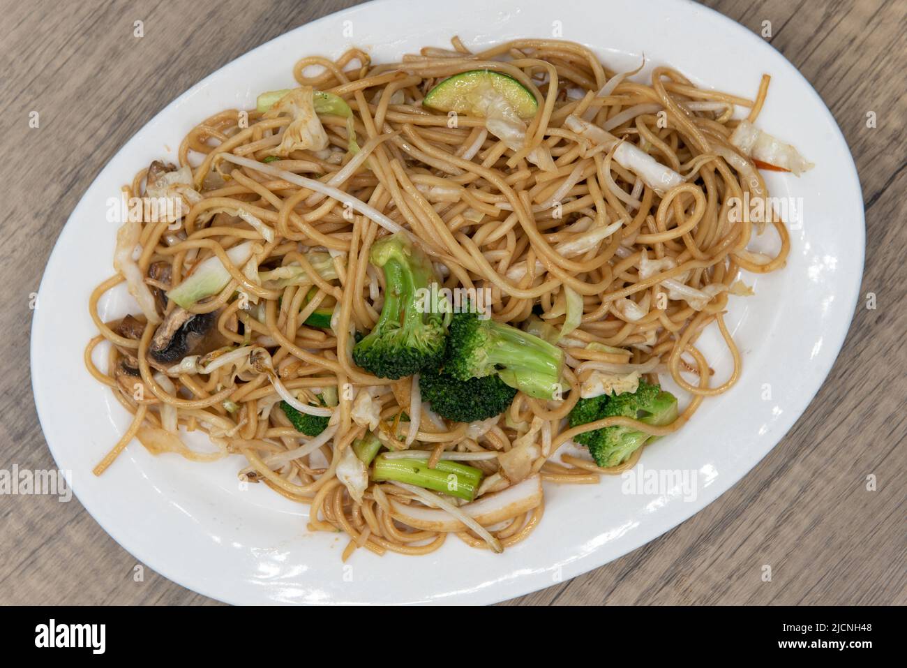 Overhead view of generous plate of vegetable noodles glazed in sauce and piled high on the plate for a great Chinese food meal. Stock Photo