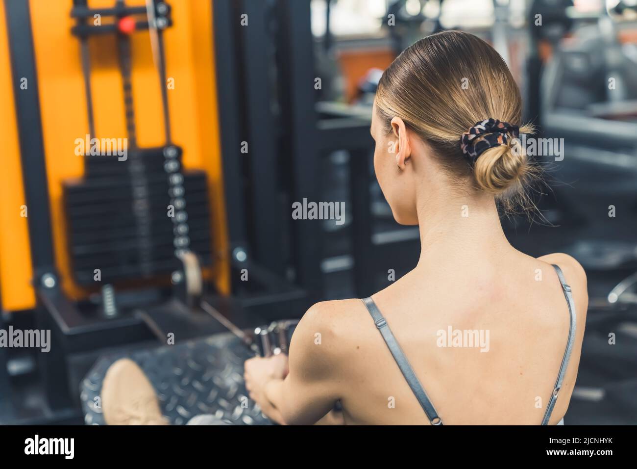 The back of a young caucasian girl with slicked back hair put into a bun exercising at the gym. Healthy living concept. High quality photo Stock Photo