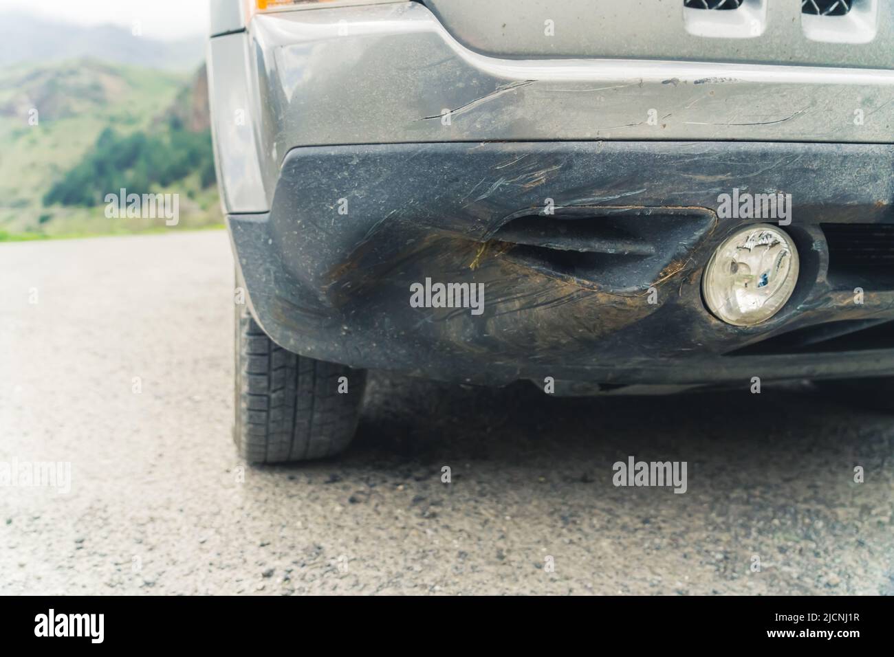 Outdoor closeup shot of a dented bumper of a car vehicle. Danger of road accidents. High quality photo Stock Photo