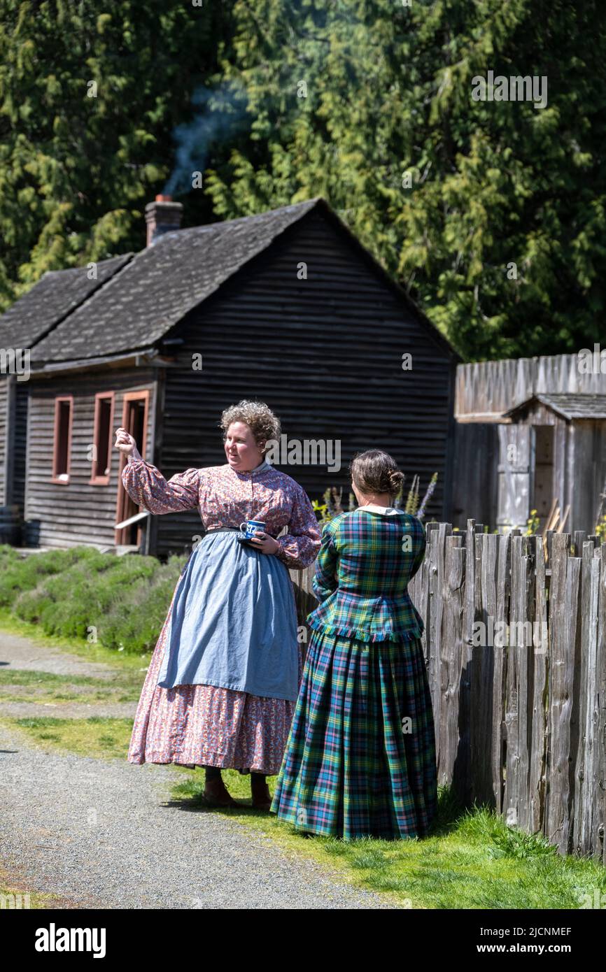 two women talking wearing traditional clothes from the 1850s at Fort Nisqually Living History Museum in Tacoma, Washington Stock Photo
