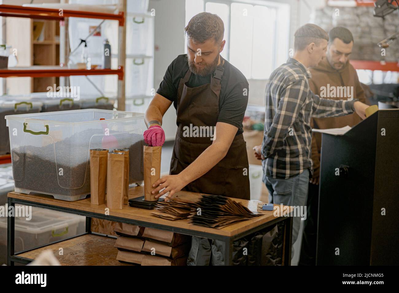 Business owner weighs paper bag with coffee beans on a scale at coffee