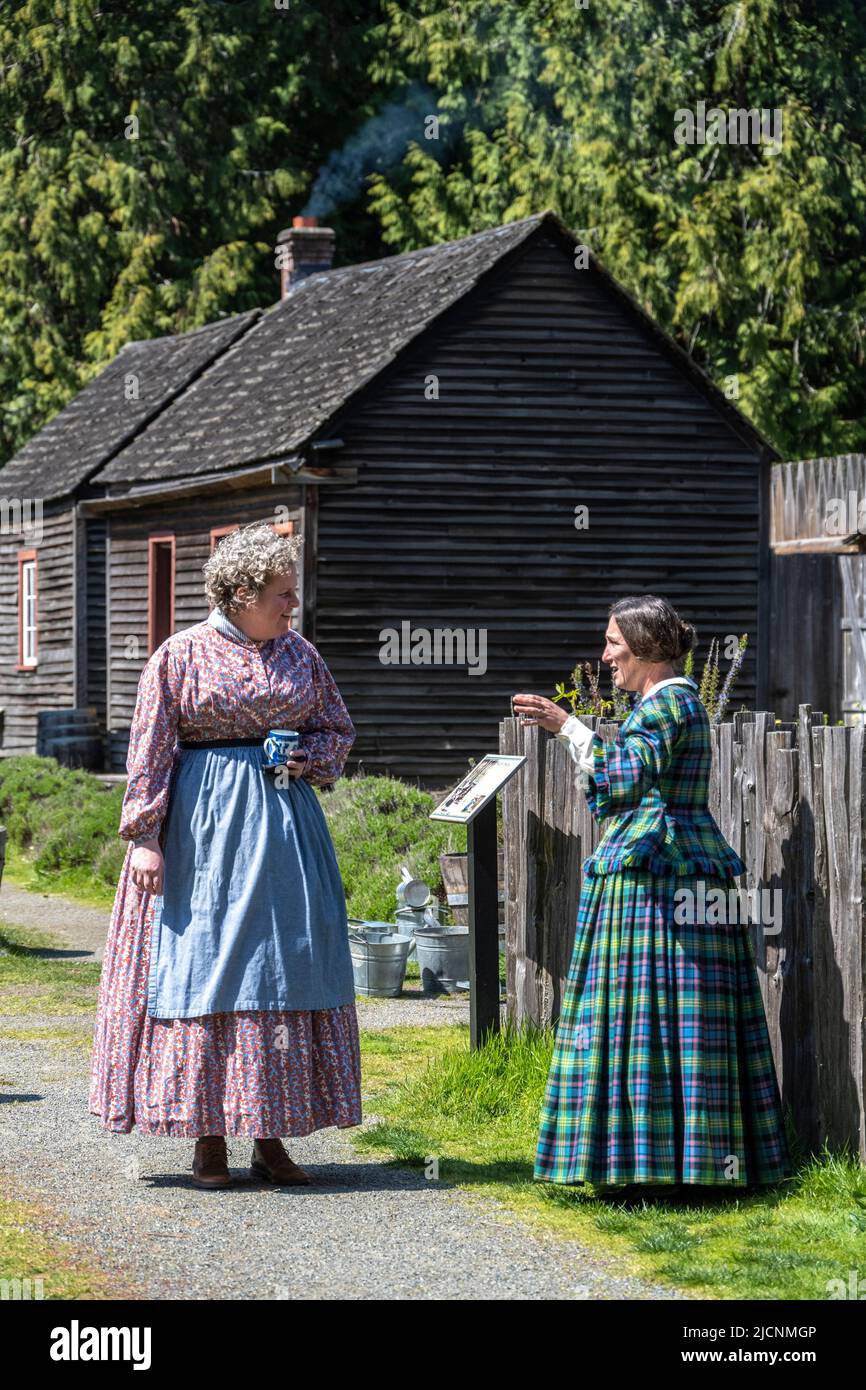 two women talking wearing traditional clothes from the 1850s at Fort Nisqually Living History Museum in Tacoma, Washington Stock Photo