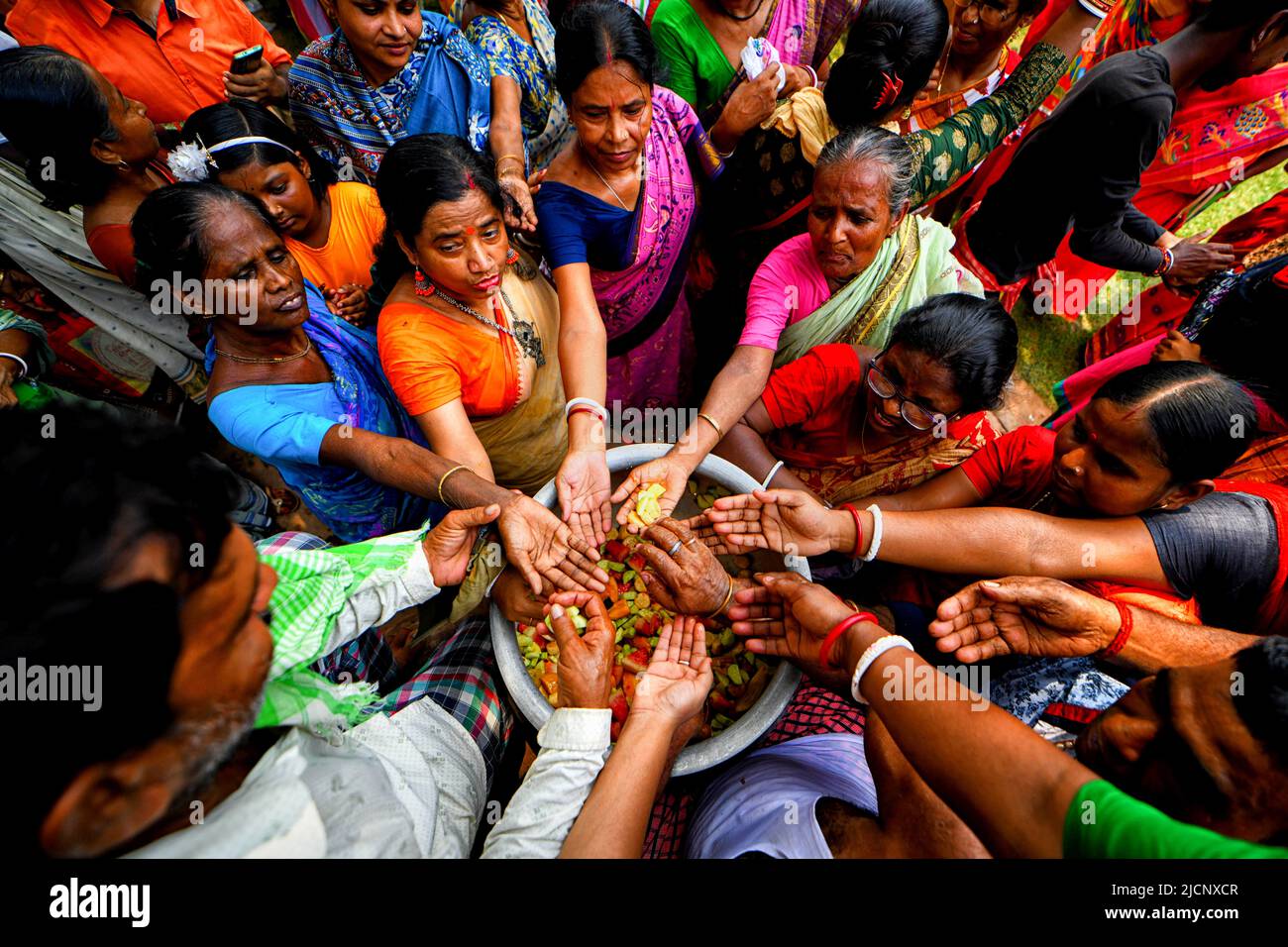 Guptipara, India. 14th June, 2022. Hindu devotees spread their hands as they receive blessings of Lord Jagannath from the Priest of Brindaban Chandra Temple. A special bath of Lord Jagannath takes place on the Purnima of Jyestha month (Devasnan Purnima), to commemorate the appearance day of Lord Jagannath. According to Skanda Purana when Raja Indradyumna installed the wooden deities he arranged this bathing ceremony. This day is considered to be the birthday of Lord jagannath. Credit: SOPA Images Limited/Alamy Live News Stock Photo