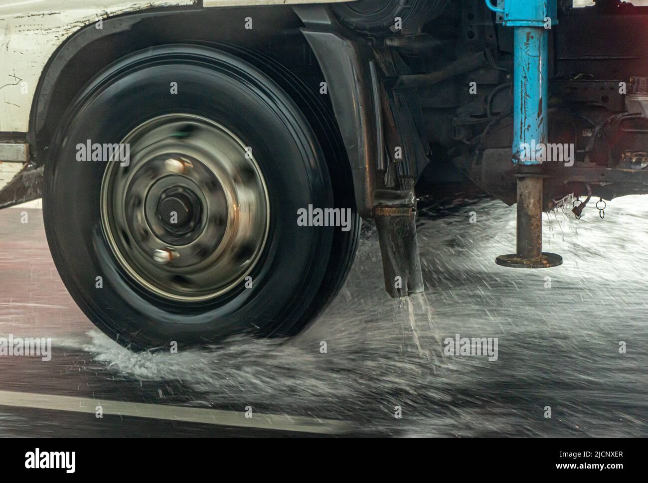 Detail of the wheel of a truck driving on a wet road. Stock Photo