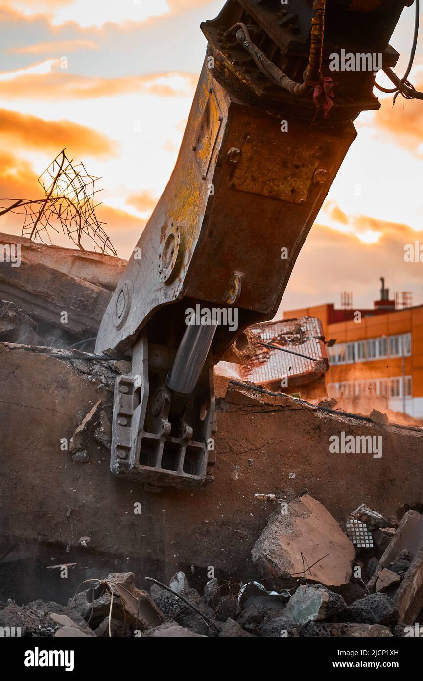 Modern crusher on excavator rigging dismantles concrete beam Stock