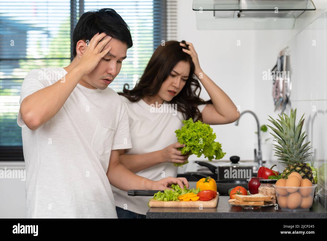 tired couple cooking and preparing vegetables in the kitchen at home Stock Photo