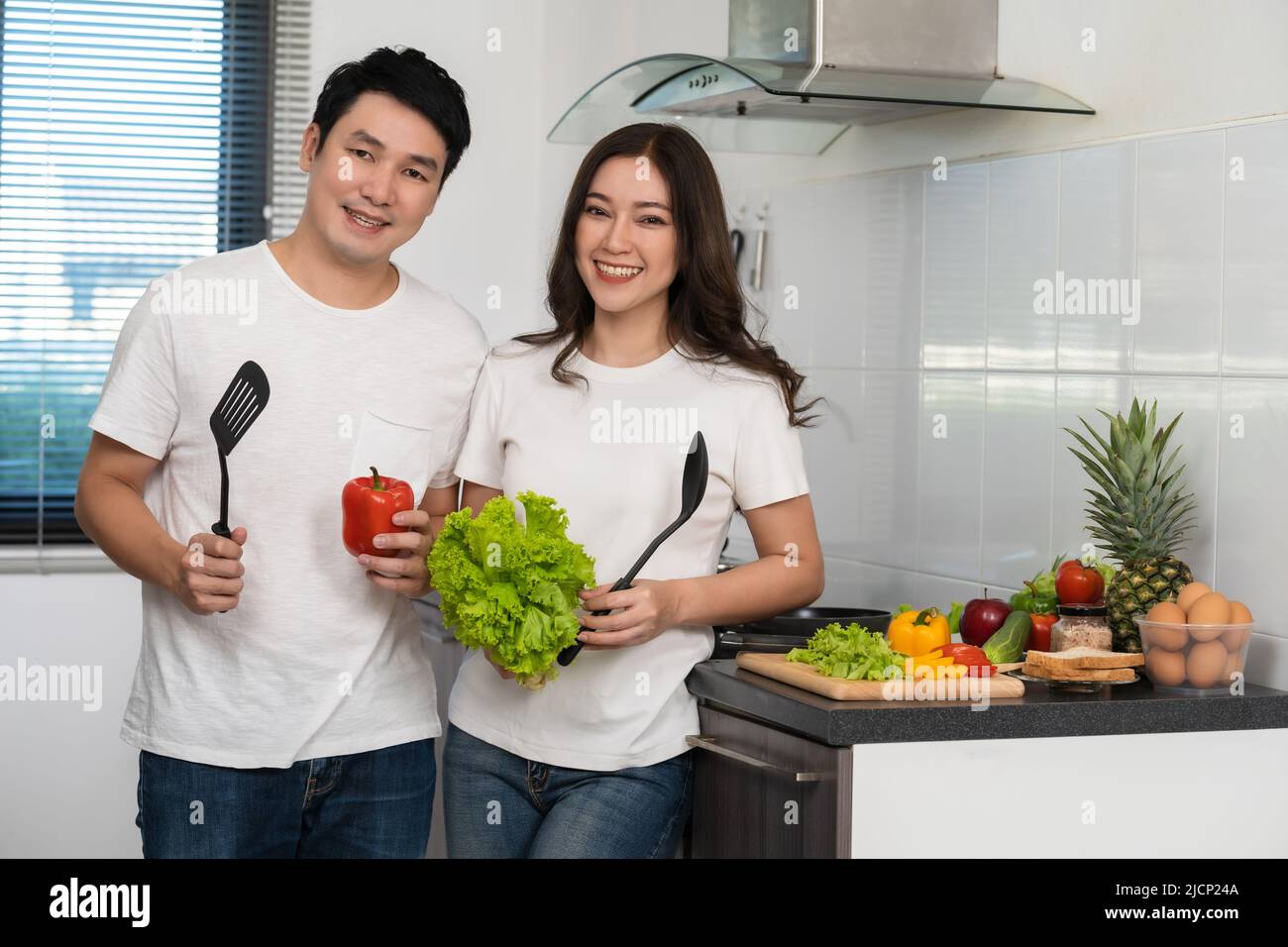 young couple cooking and preparing vegetables in the kitchen at home Stock Photo