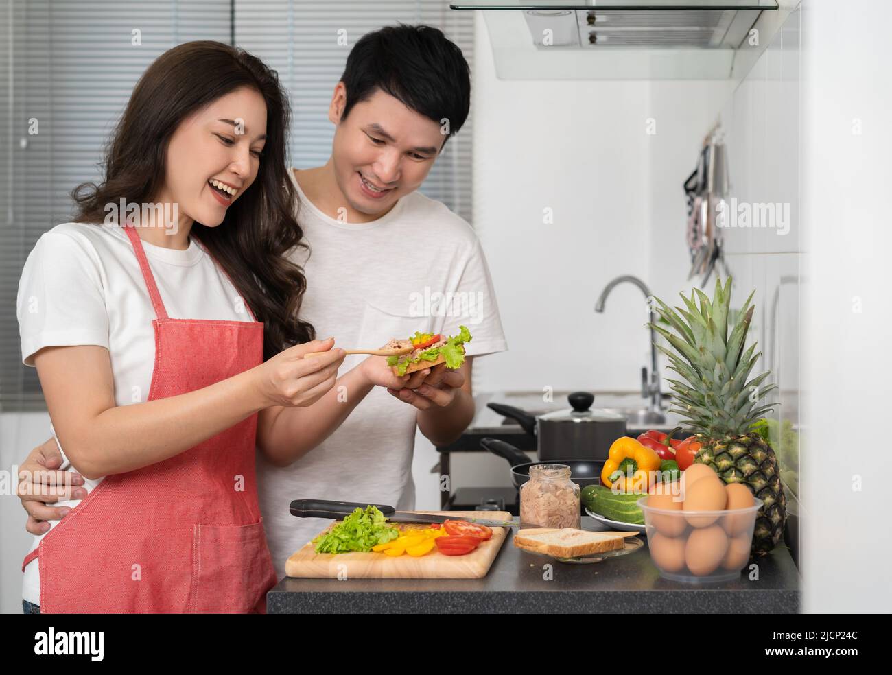 young couple cooking sandwich together in the kitchen at home Stock Photo