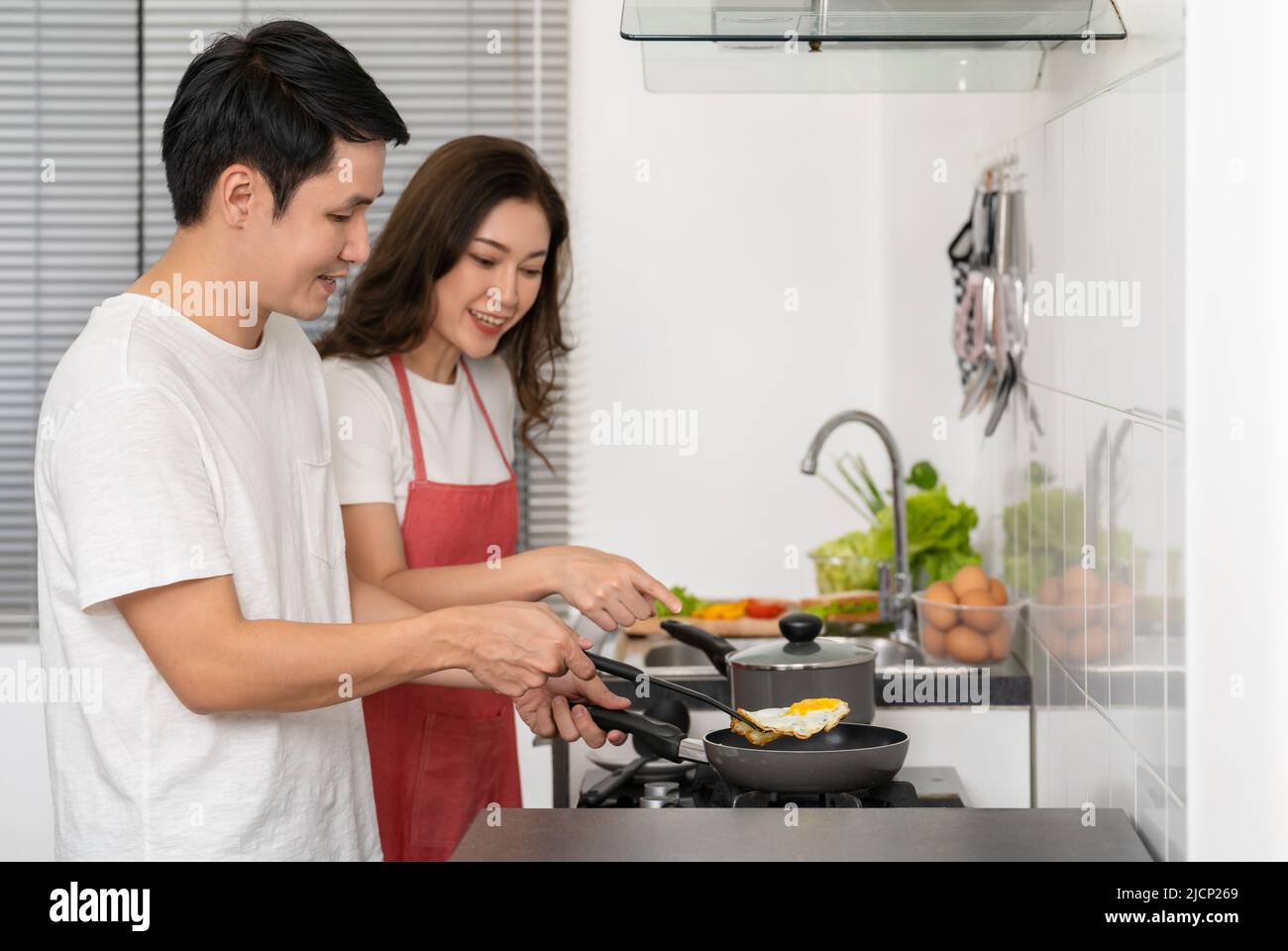 happy young couple cooking and preparing food in the kitchen at home Stock Photo