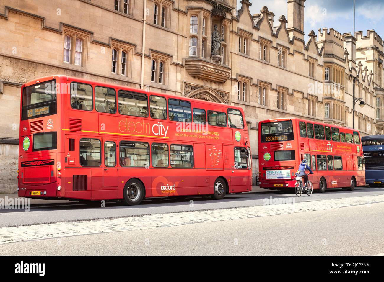 6 June 2019: Oxford, UK - Electric hybrid double decker buses in the High Street, with a cyclist passing by. Stock Photo