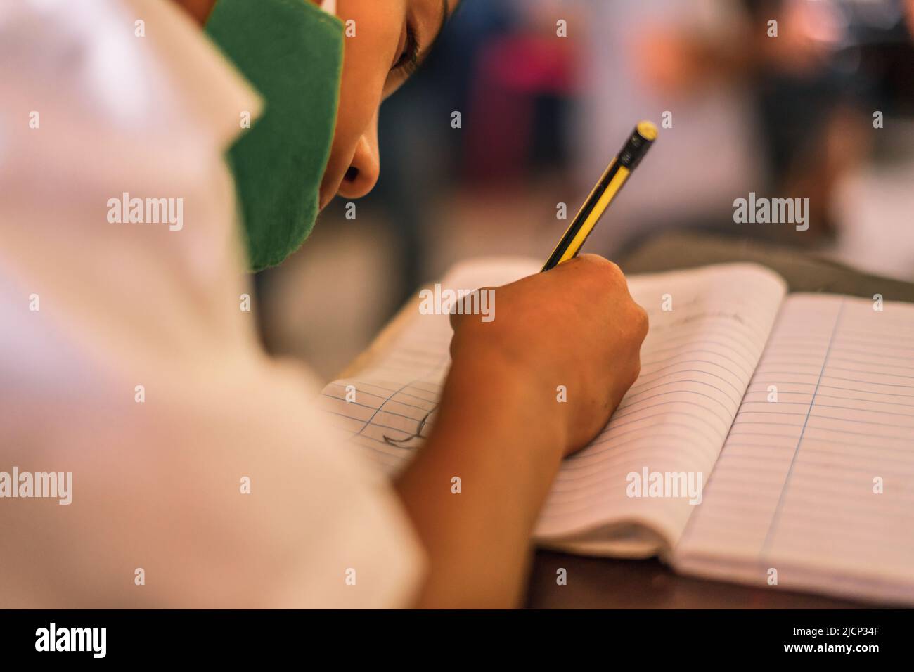 Nicaraguan boy with medical mask writing on his notebook at a desk Stock Photo