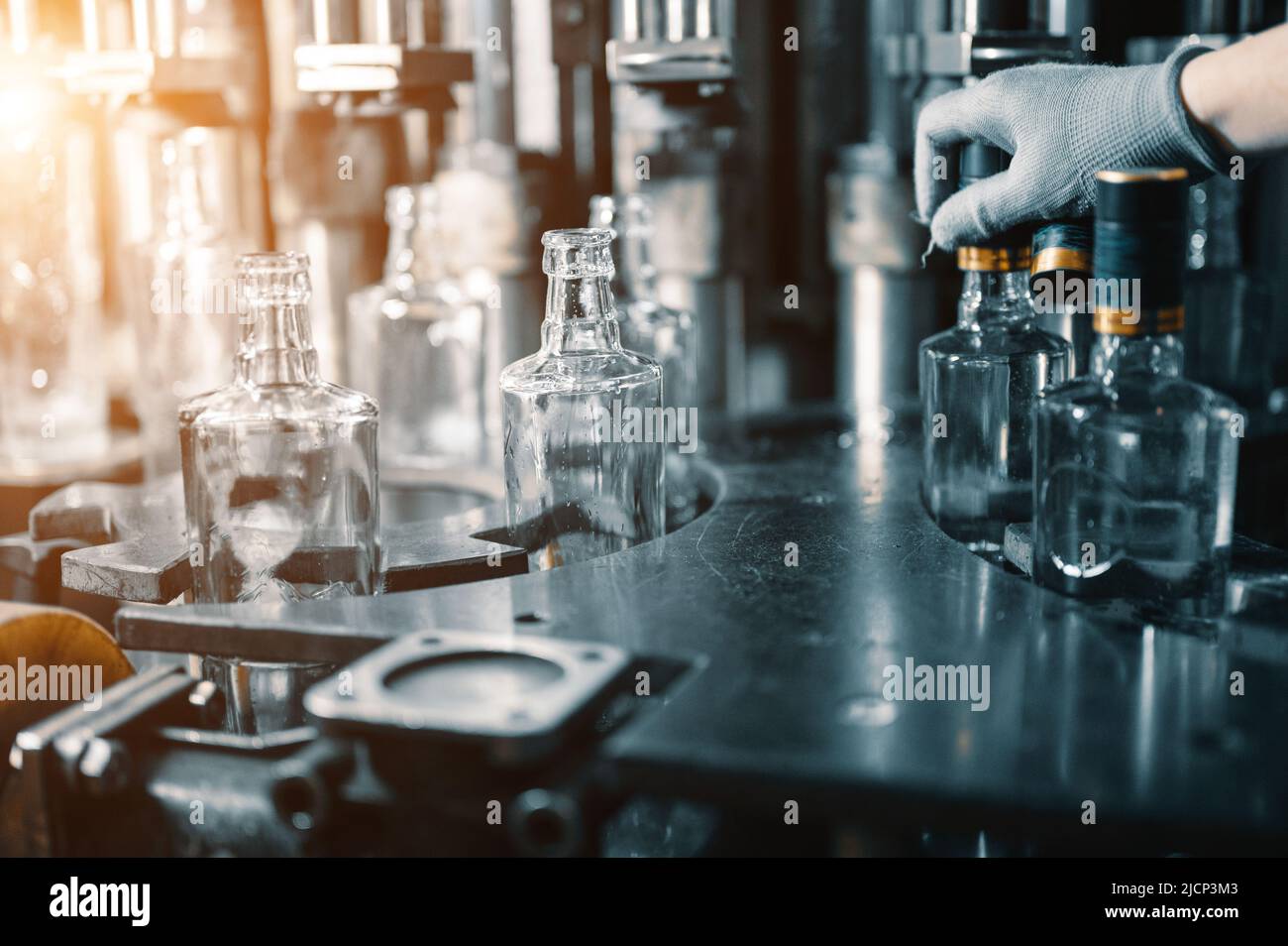 Worker puts plastic cap on bottle of luxury vodka in shop Stock Photo