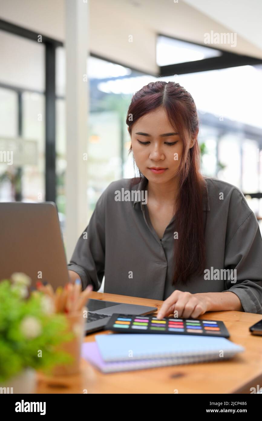 Portrait, Beautiful millennial Asian female graphic designer concentrated working on the project at her office desk. Stock Photo