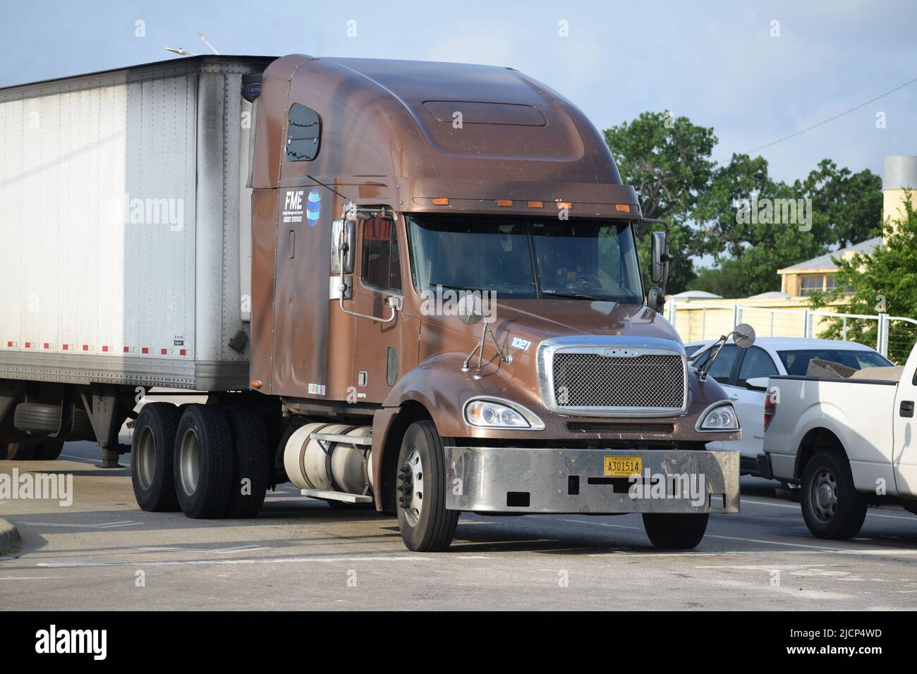 An AfricanAmerican man driving a semitruck and trailer through