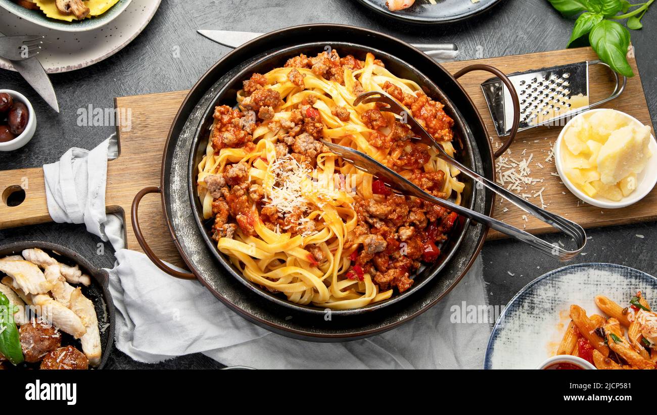 Table of italian meals on plates pasta Bolognese, ravioli, penne with