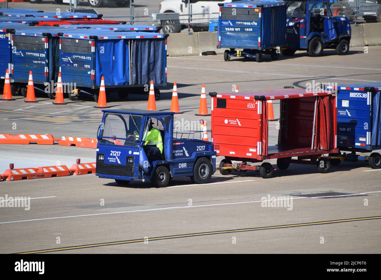 An American Airlines ramp services worker driving a tractor pulling