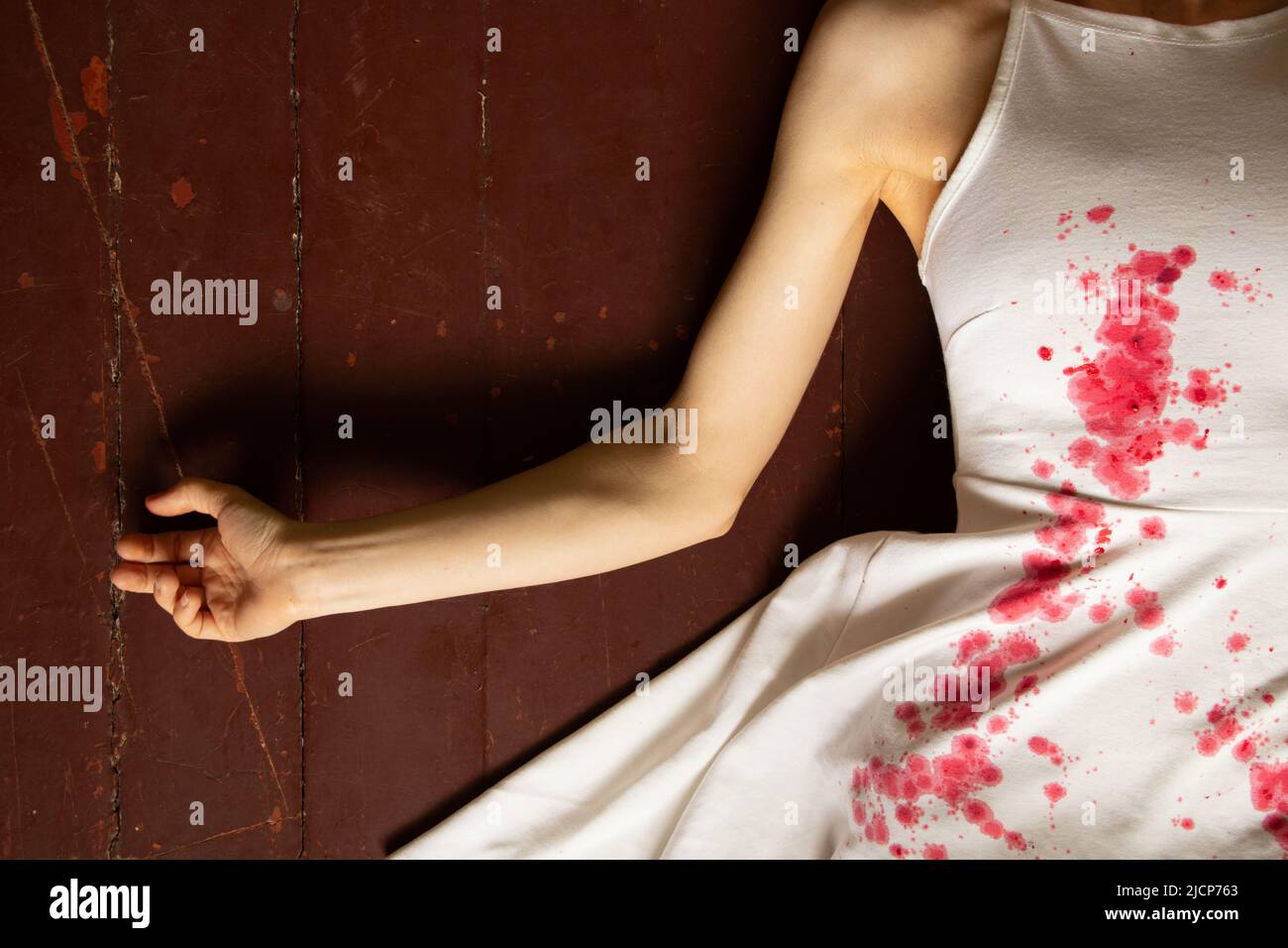 A murdered and tortured Ukrainian woman in a white dress and bloodstains lies on the floor of the house, a protest action by Ukrainian women, protecti Stock Photo