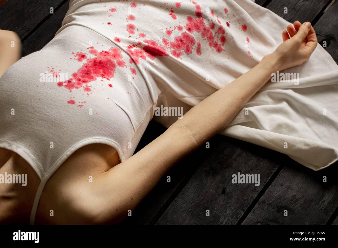 A murdered and tortured Ukrainian woman in a white dress and bloodstains lies on the floor of the house, a protest action by Ukrainian women, protecti Stock Photo