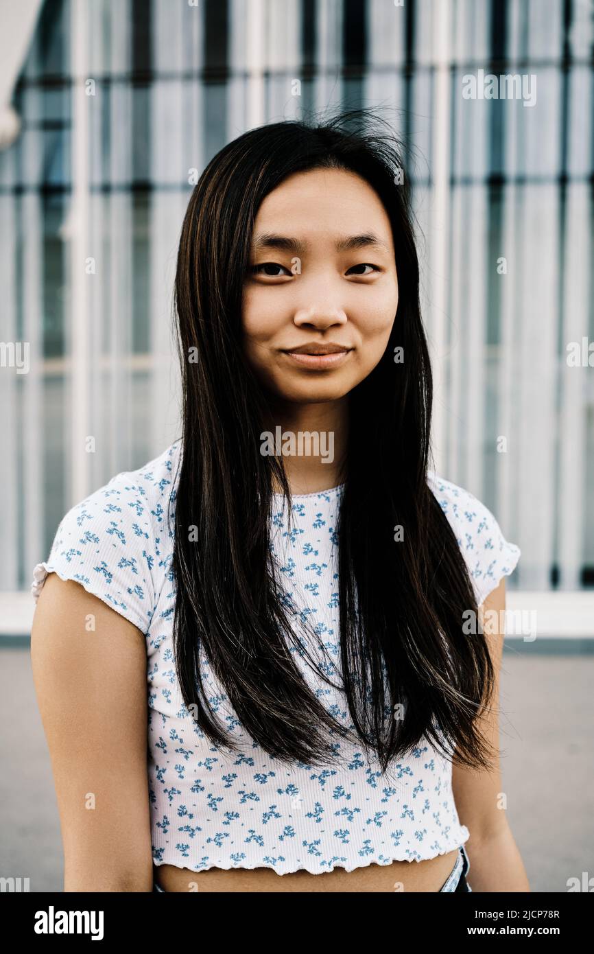 Portrait of a young Asian woman smiles at camera while standing outdoors. Stock Photo