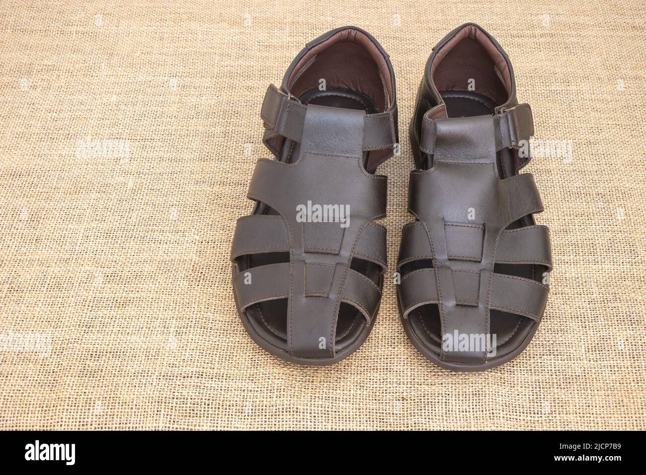 Close up shot of brown sandals for men and a rustic fabric background