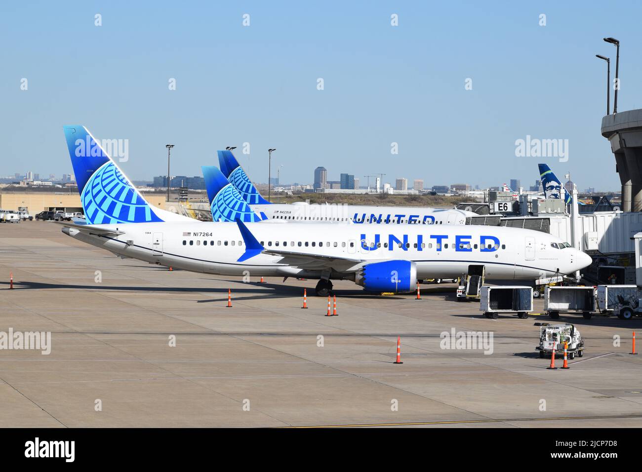 Three United Airlines planes parked and being serviced by ramp agents at terminal E at Dallas