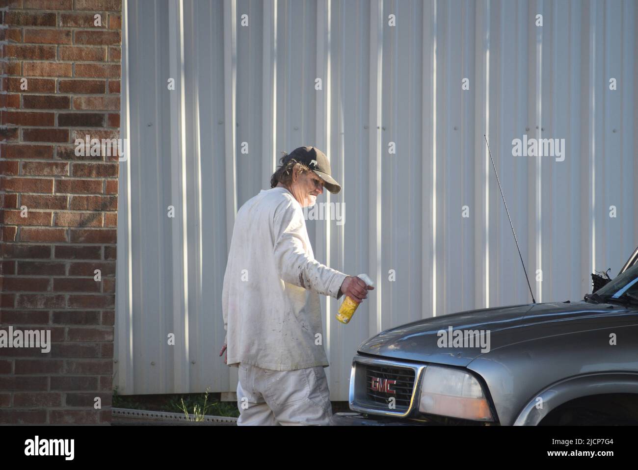 Man spraying polish or cleaner on the hood of his GMC SUV Stock Photo