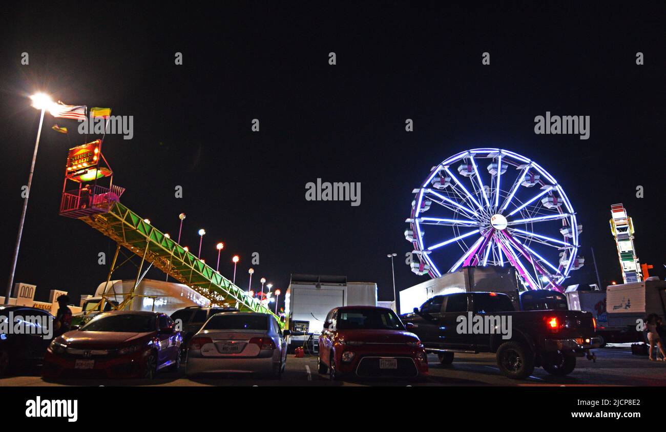 Night view of carnival rides, including a ferris wheel, at a carnival outside of Irving Mall in Irving, Texas Stock Photo