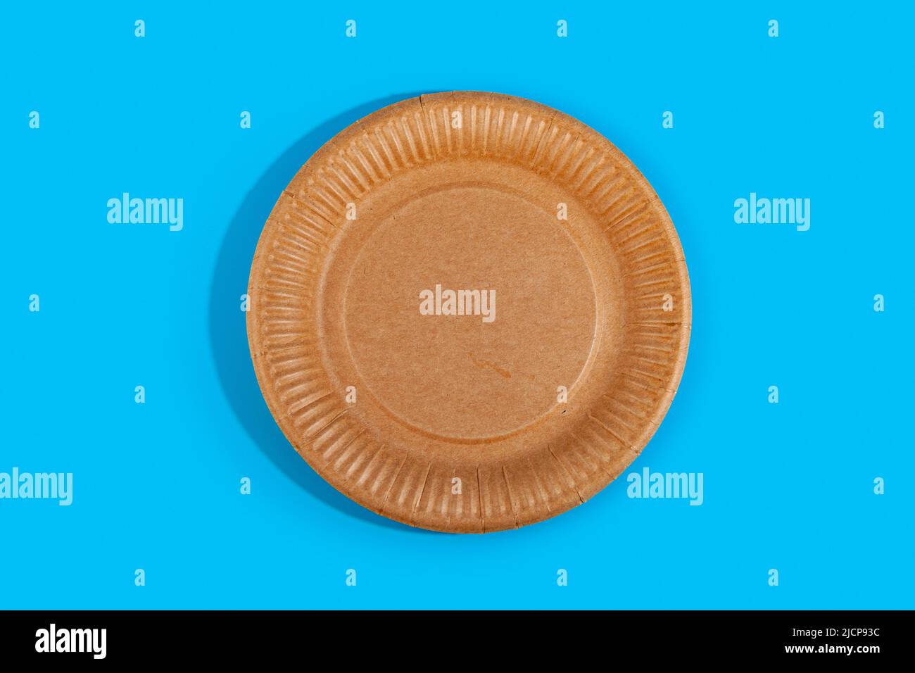 Disposable paper biodegradable plate on a blue background. Top view. Flat lay composition. Stock Photo