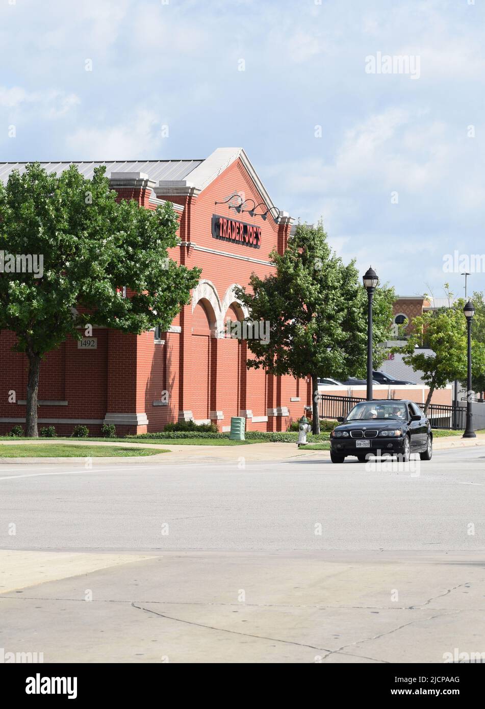 A black BMW car stopped at a traffic light next to a Trader Joe's grocery store in Southlake Texas Stock Photo