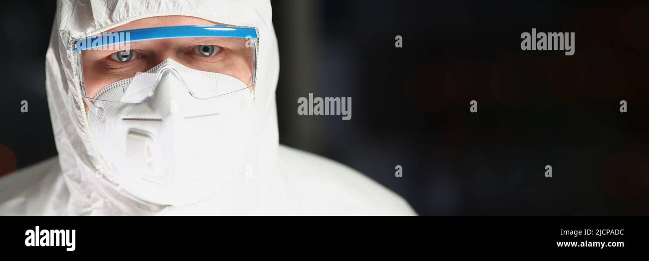 Worker in protective respirator and white coverall analyzing science experiment Stock Photo
