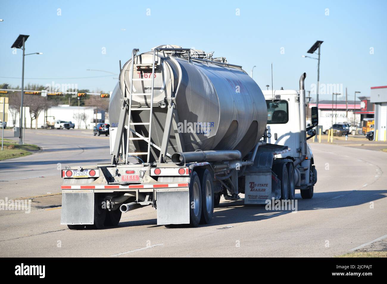 A semitruck with tanker trailer driving away from the camera Stock
