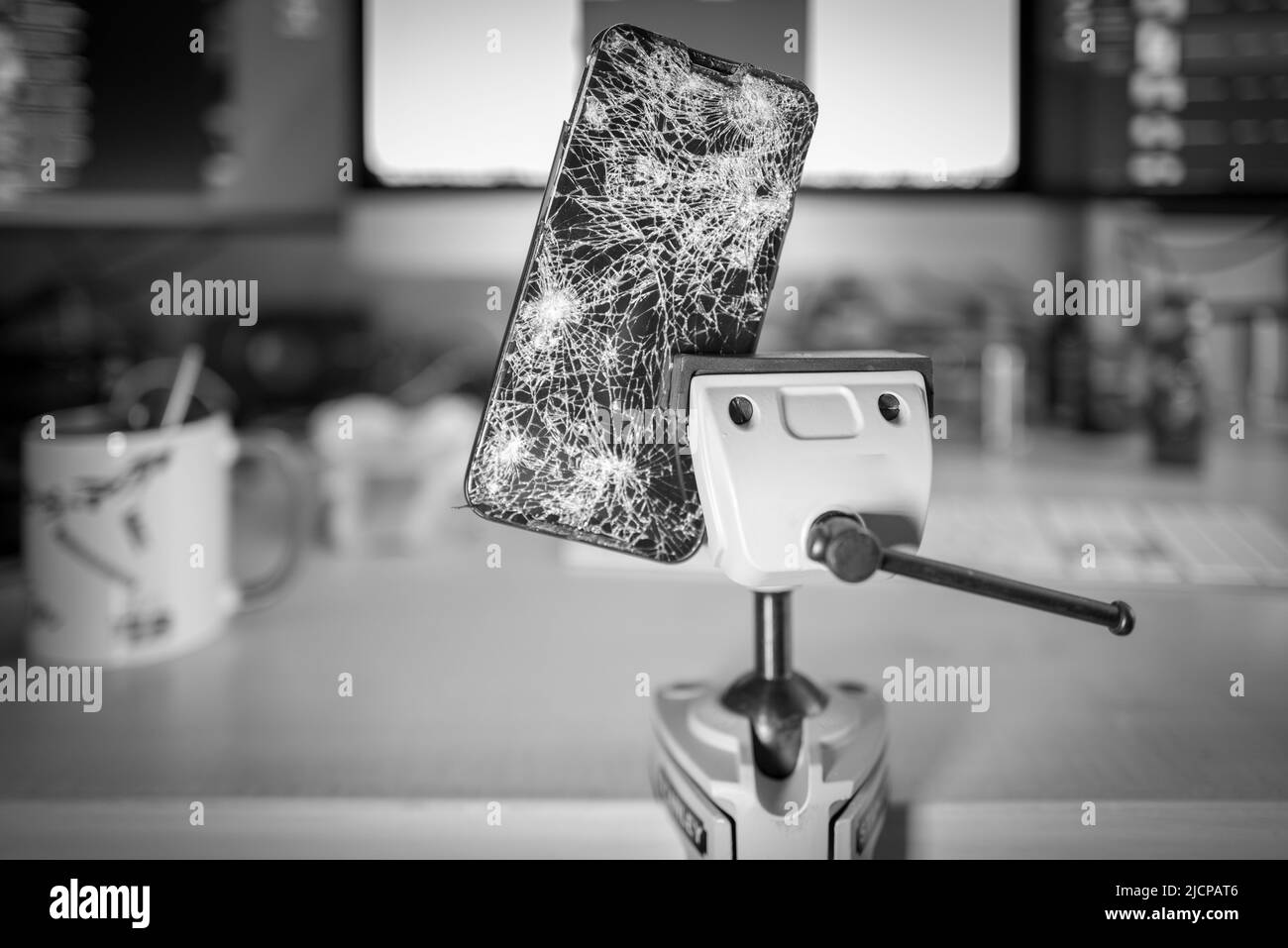 a completely destroyed cell phone is clamped in a vice Stock Photo