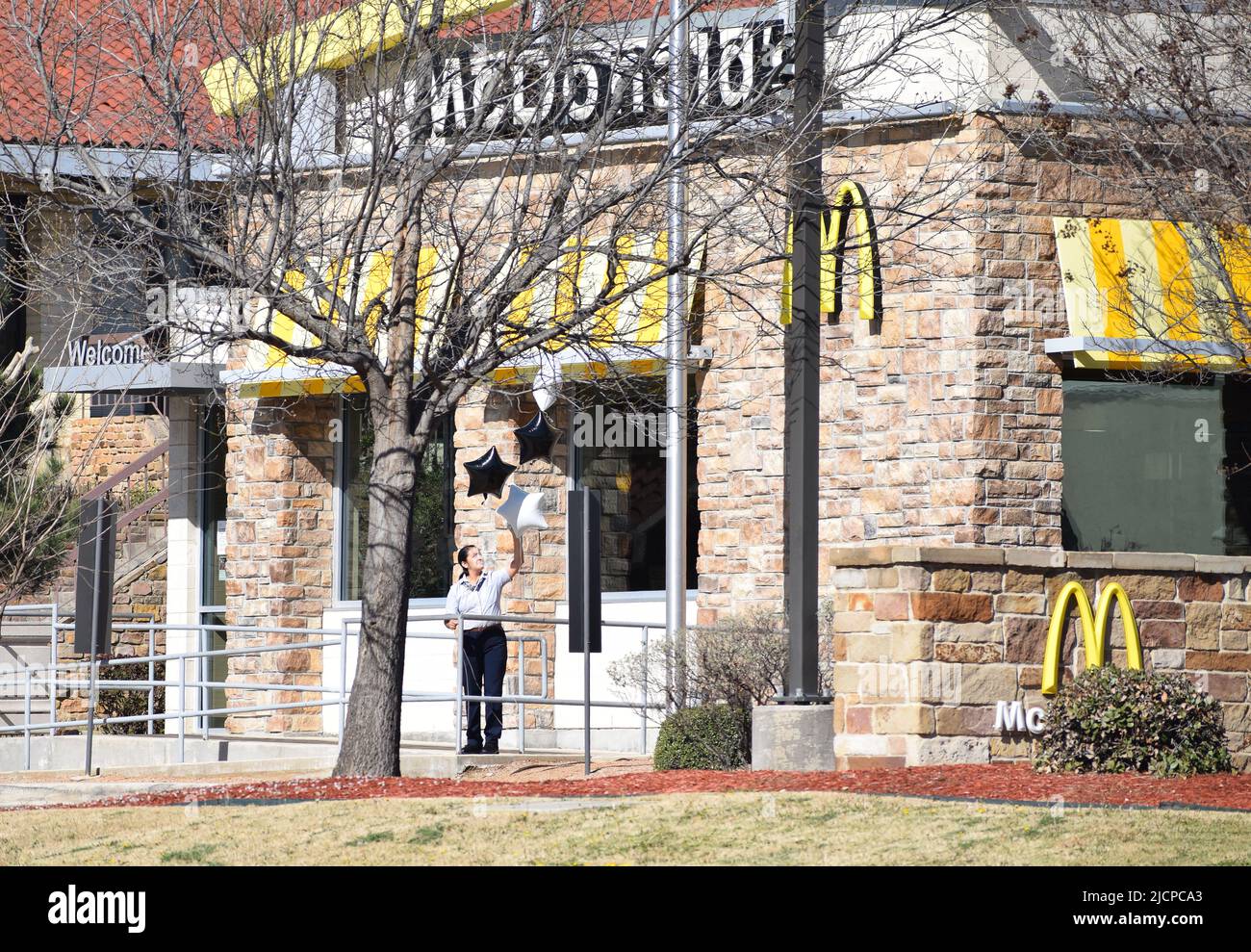 McDonald's Restaurant manager decorating the outside of her store with black and white balloons Stock Photo